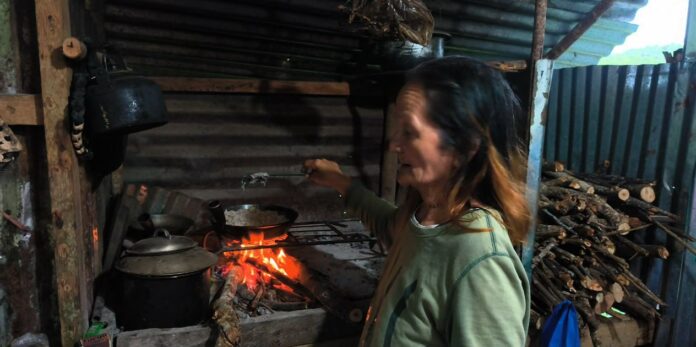 A local woman cooks dinner in an outdoor kitchen with a wood-burning fire in Barangay Cambanac.
